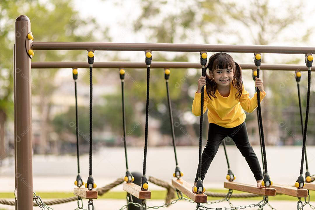 conceito de verão, infância, lazer e pessoas - menina feliz no quadro de escalada do parque infantil