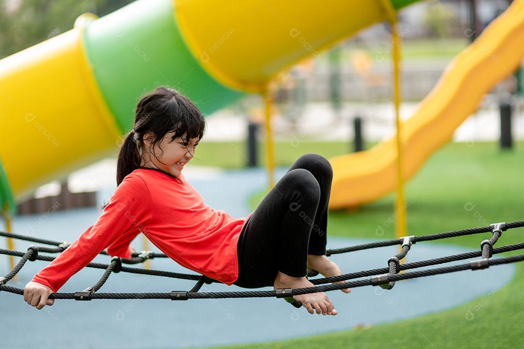 conceito de verão, infância, lazer e pessoas - menina feliz no quadro de escalada do parque infantil