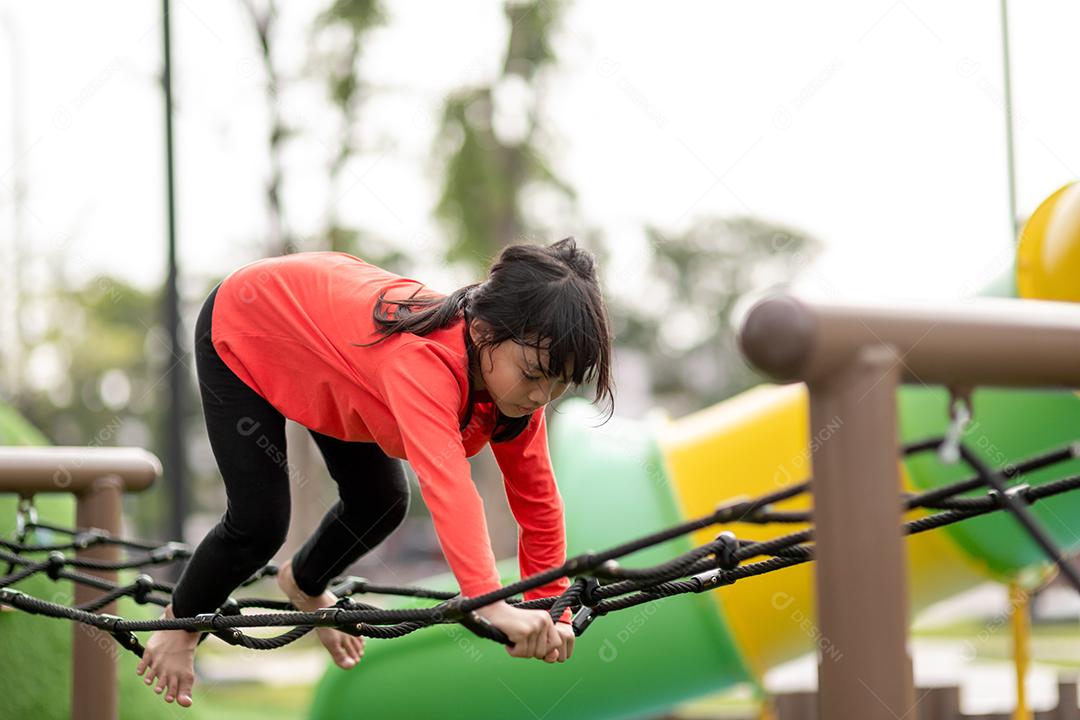 conceito de verão, infância, lazer e pessoas - menina feliz no quadro de escalada do parque infantil