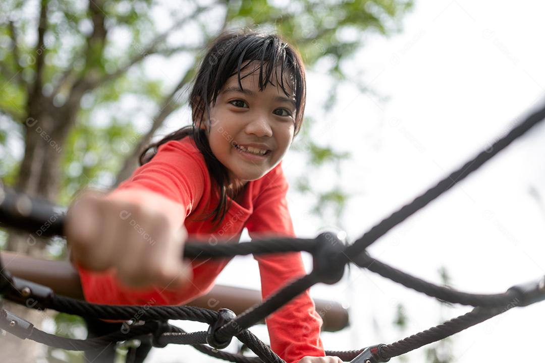 conceito de verão, infância, lazer e pessoas - menina feliz no quadro de escalada do parque infantil