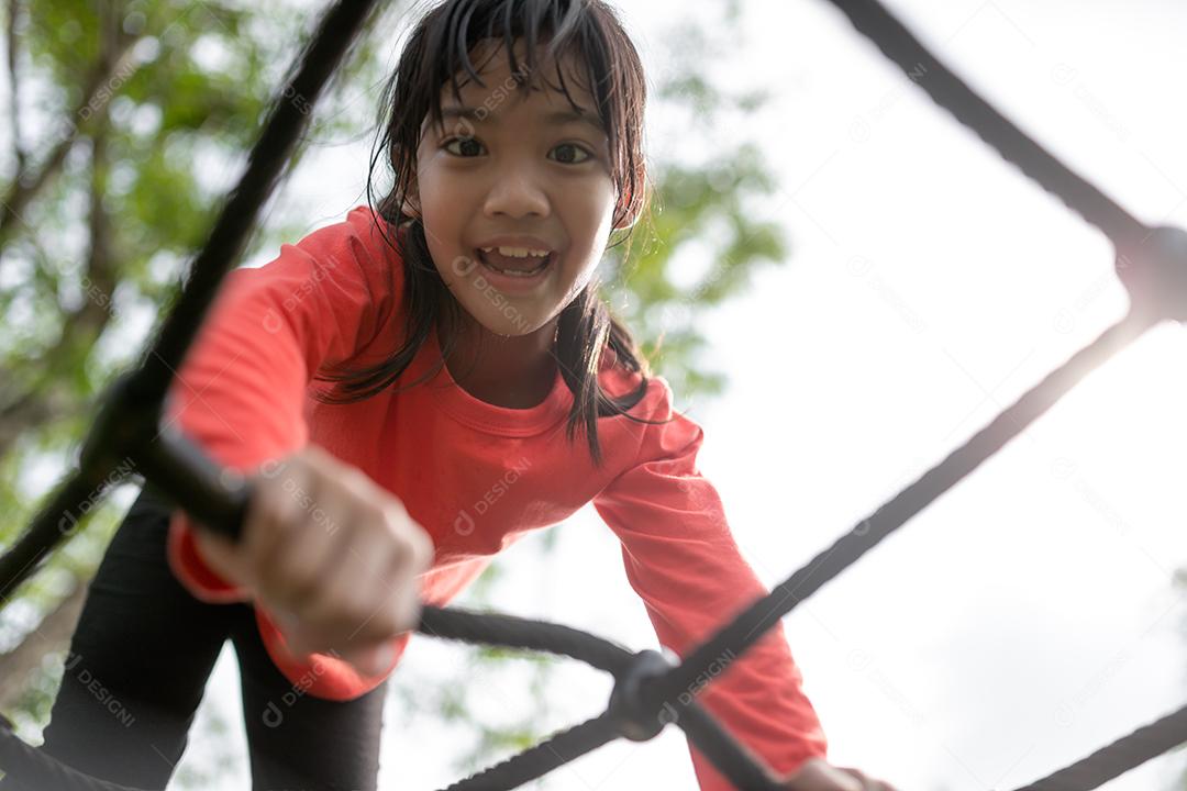 conceito de verão, infância, lazer e pessoas - menina feliz no quadro de escalada do parque infantil