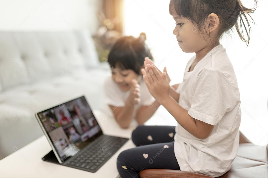 Menina asiática tendo aula on-line e feliz pelo conceito de pandemia de coranavírus de quarentena escolar em casa