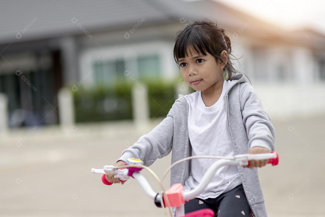 Crianças aprendendo a dirigir uma bicicleta em uma garagem do lado de fora. Meninas andando de bicicleta na estrada de asfalto na cidade