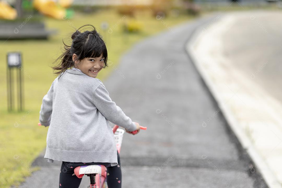 menina criança alegre feliz andando de bicicleta no parque na natureza