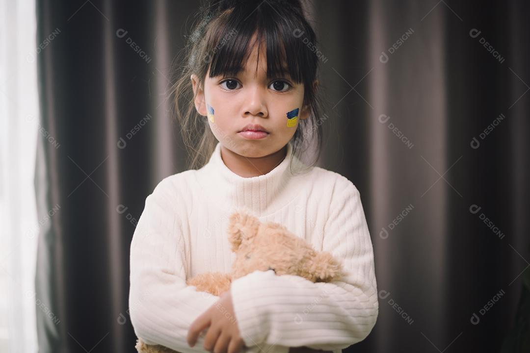 Uma criança com a bandeira da Ucrânia está chorando. Tristeza desejando esperança. As lágrimas das crianças da guerra. Evacuação de civis. Liberdade para a Ucrânia