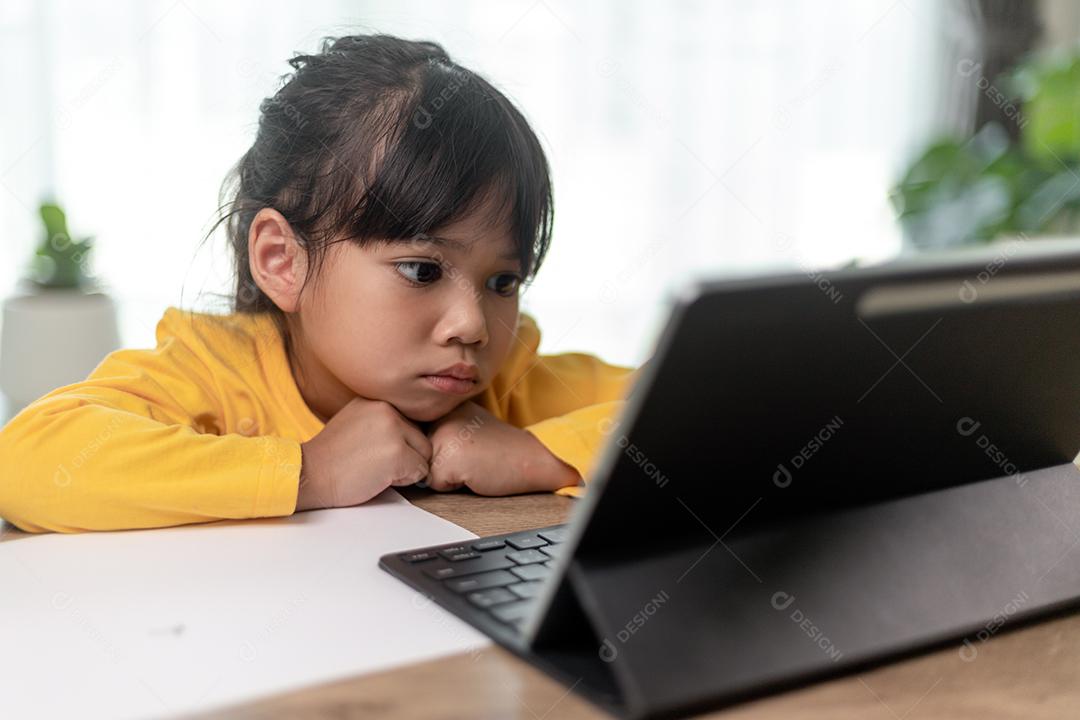 Menina asiática tendo aula on-line e feliz pelo conceito de pandemia de coranavírus de quarentena escolar em casa