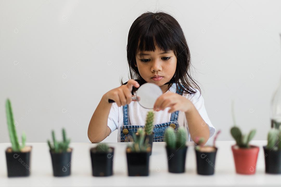 Menina asiática está plantando plantas em casa, conceito de atividade de aprendizado de crescimento de plantas para uma criança pré-escolar e educação infantil para a árvore na natureza