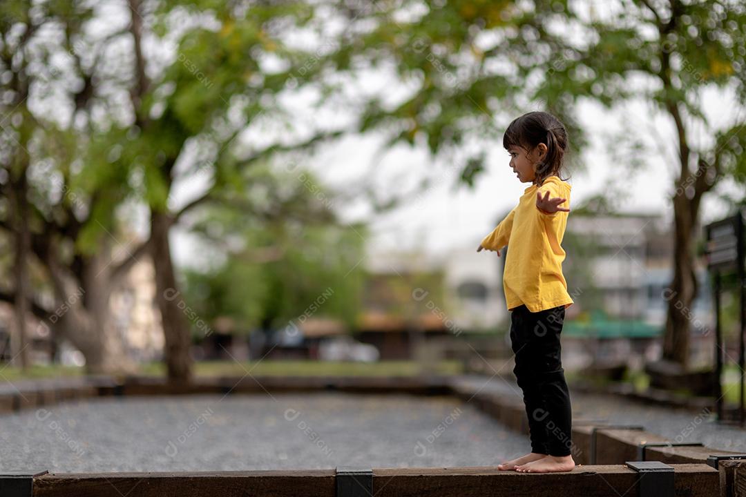 Menina asiática brincando no playground no parque ao ar livre Momento feliz e boa emoção