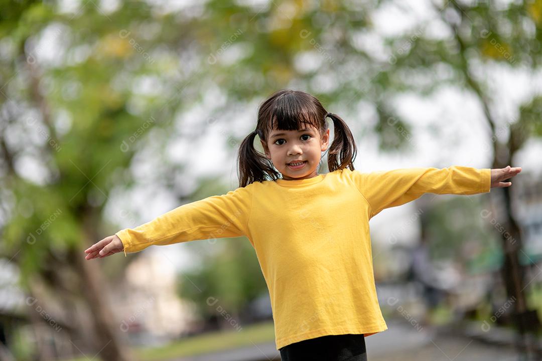Menina asiática brincando no playground no parque ao ar livre Momento feliz e boa emoção