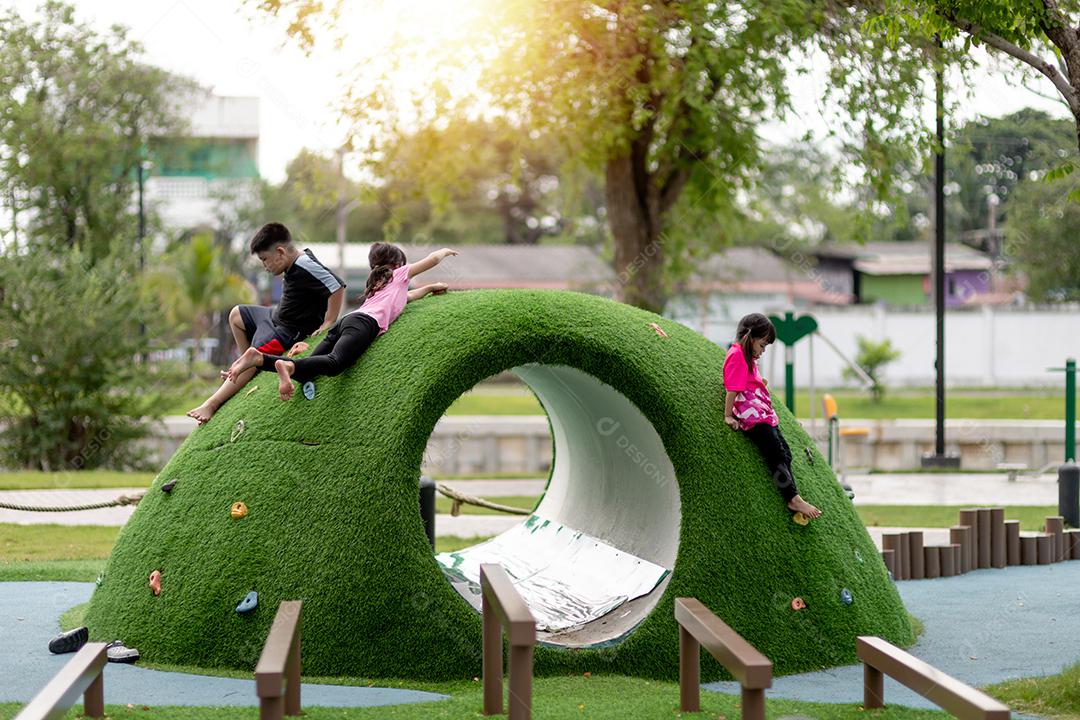 As crianças bonitas estão descansando no playground no verão