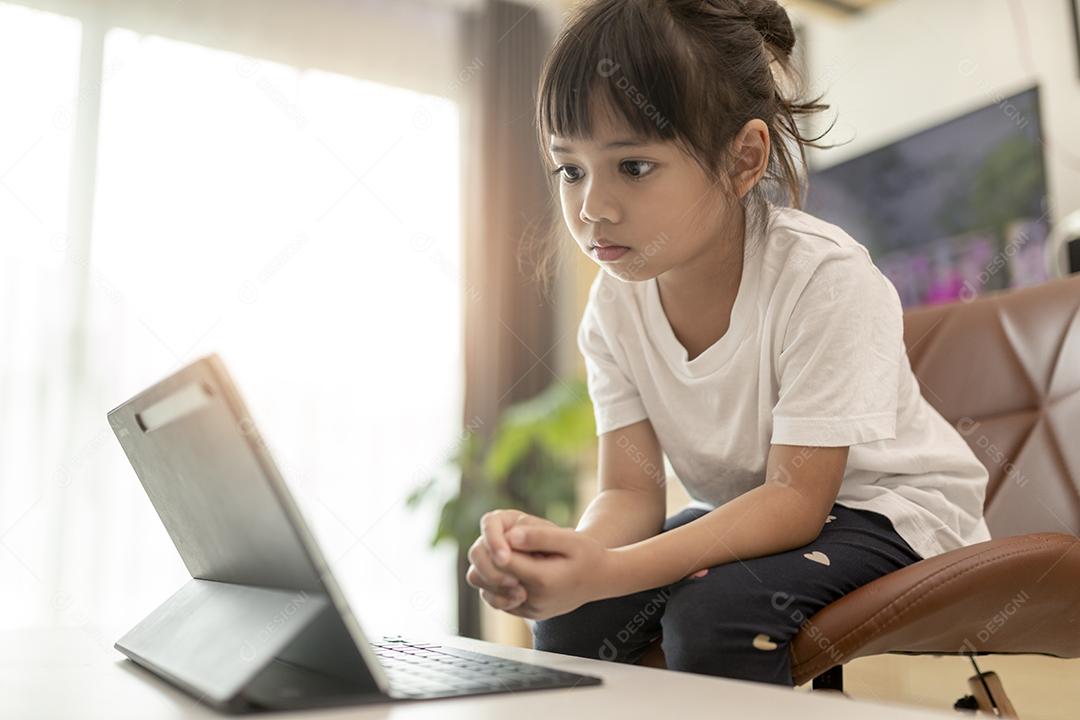 Linda colegial estudando lição de casa durante sua aula online em casa, distância social durante a quarentena, auto-isolamento, conceito de educação online, homeschooler