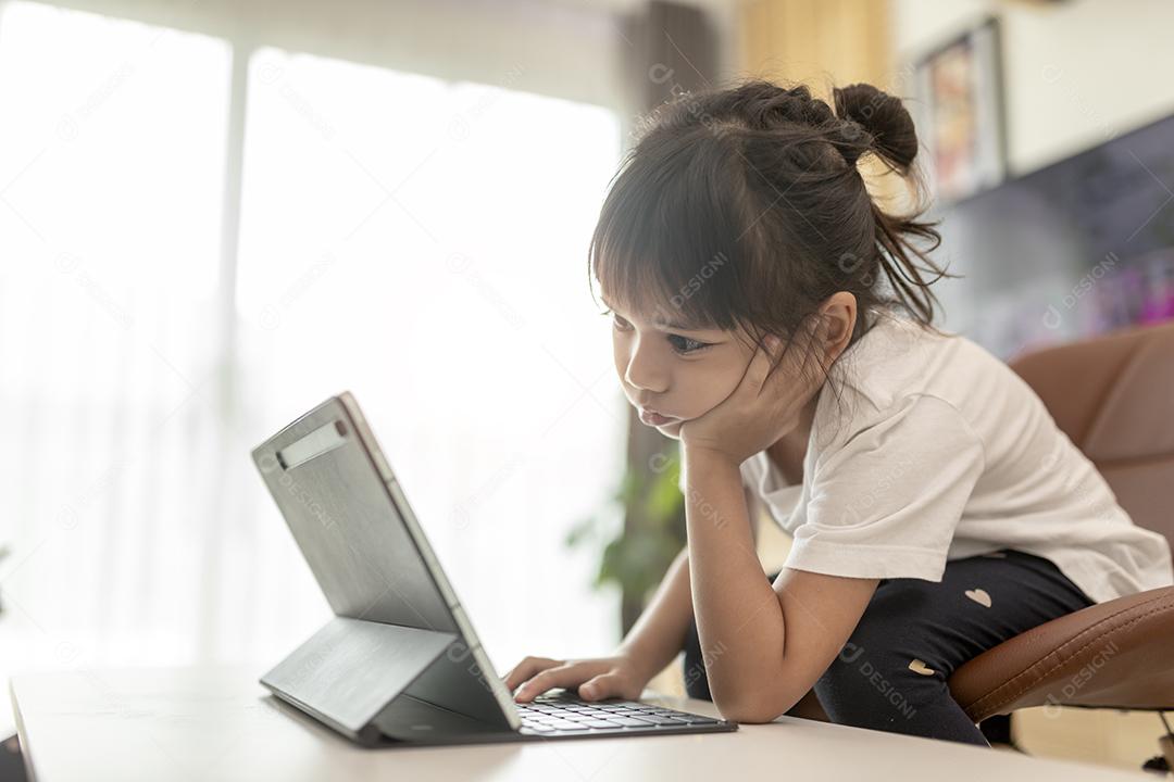 Linda colegial estudando lição de casa durante sua aula online em casa, distância social durante a quarentena, auto-isolamento, conceito de educação online, homeschooler