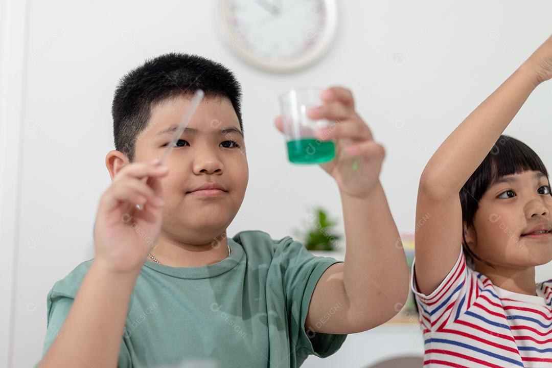 Crianças asiáticas assistem com entusiasmo aos experimentos de química.
