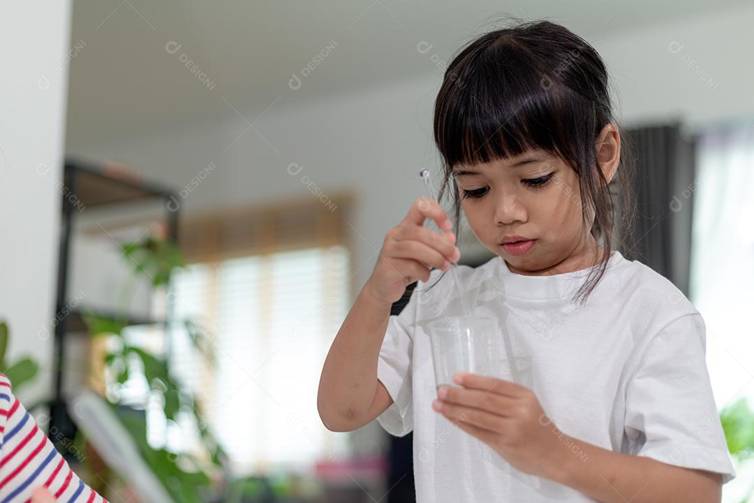 Crianças asiáticas assistem com entusiasmo aos experimentos de química.