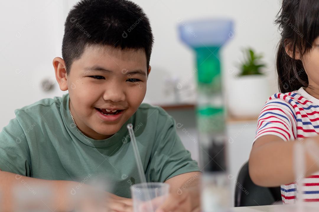Crianças asiáticas assistem com entusiasmo aos experimentos de química.