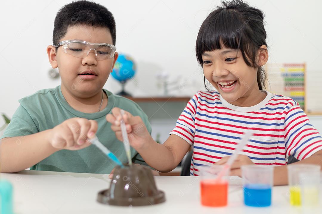 Crianças repetindo e observando um projeto de laboratório de ciências em casa - o vulcão de bicarbonato de sódio e vinagre