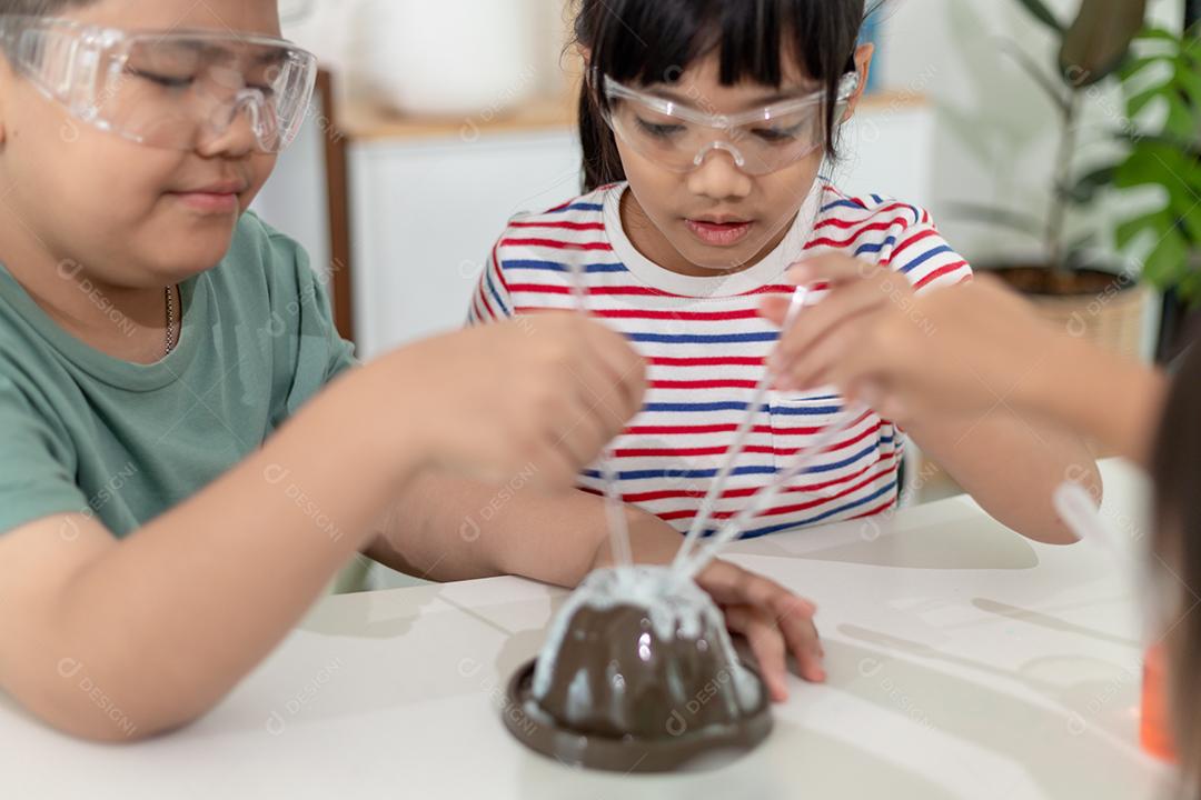 Crianças repetindo e observando um projeto de laboratório de ciências em casa - o vulcão de bicarbonato de sódio e vinagre