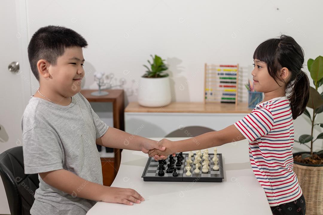 Menino e menina estão jogando xadrez em casa. Crianças jogando xadrez