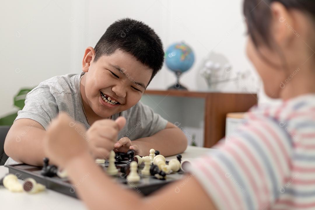 Menino e menina estão jogando xadrez em casa. Crianças jogando xadrez
