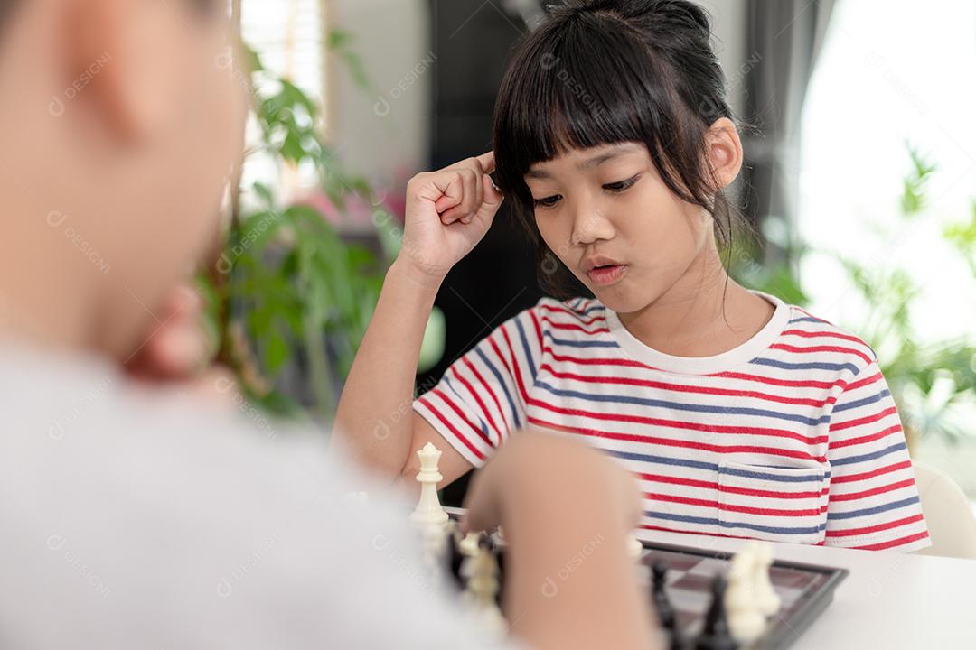 Menino e menina estão jogando xadrez em casa. Crianças jogando xadrez