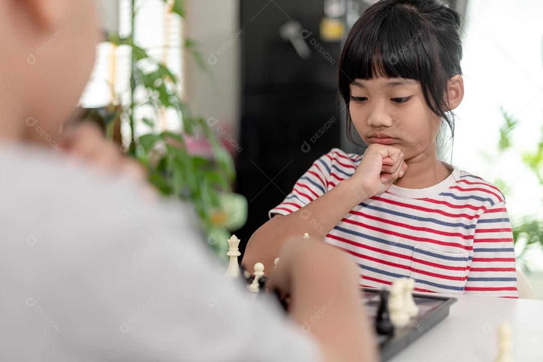 Menino e menina estão jogando xadrez em casa. Crianças jogando xadrez