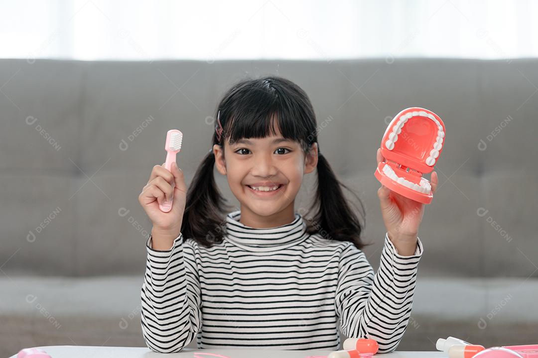 Uma criança pequena brinca com mandíbulas artificiais. Odontologia infantil.