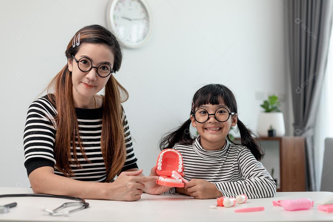 Mãe ensina sua filha criança a escovar os dentes com precisão