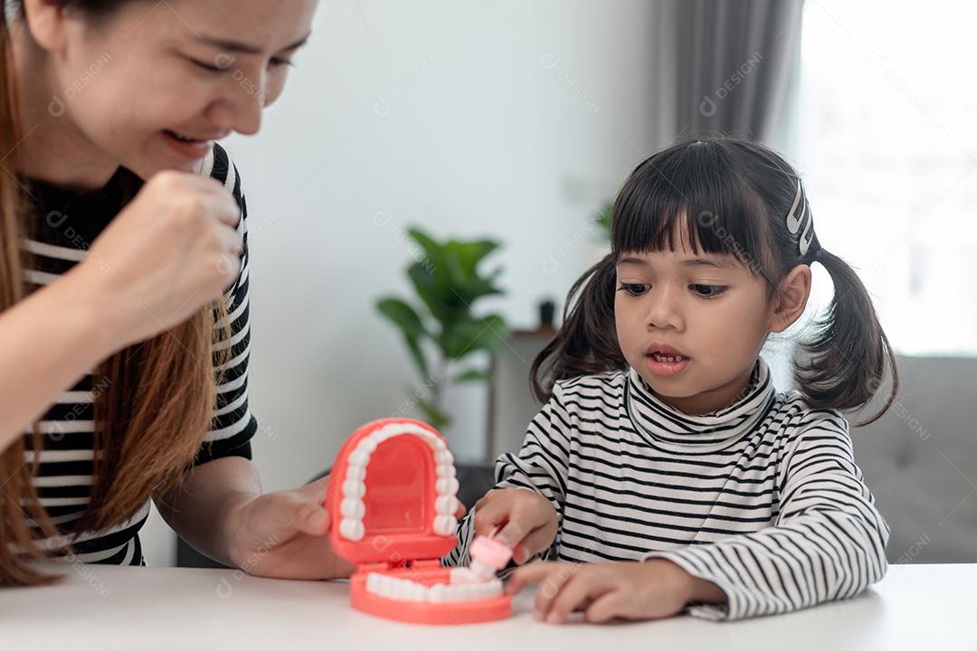Mãe ensina sua filha criança a escovar os dentes com precisão