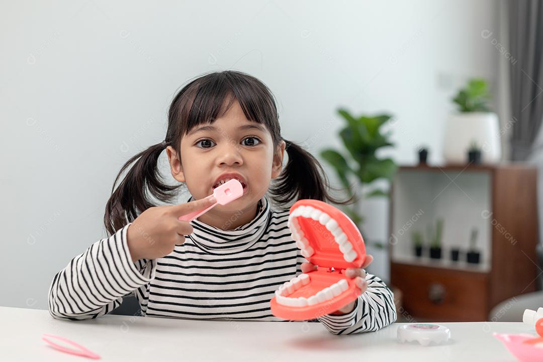 Uma criança pequena brinca com mandíbulas artificiais. Odontologia infantil.
