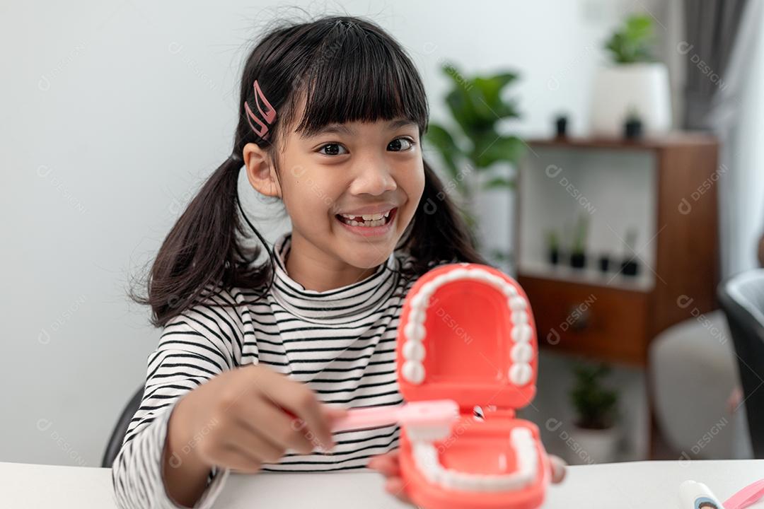 Uma criança pequena brinca com mandíbulas artificiais. Odontologia infantil.