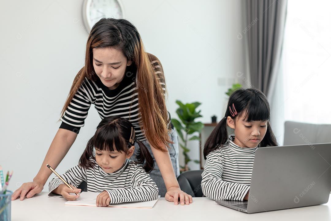 Garotinha asiática aprendendo aula online em casa com mãe