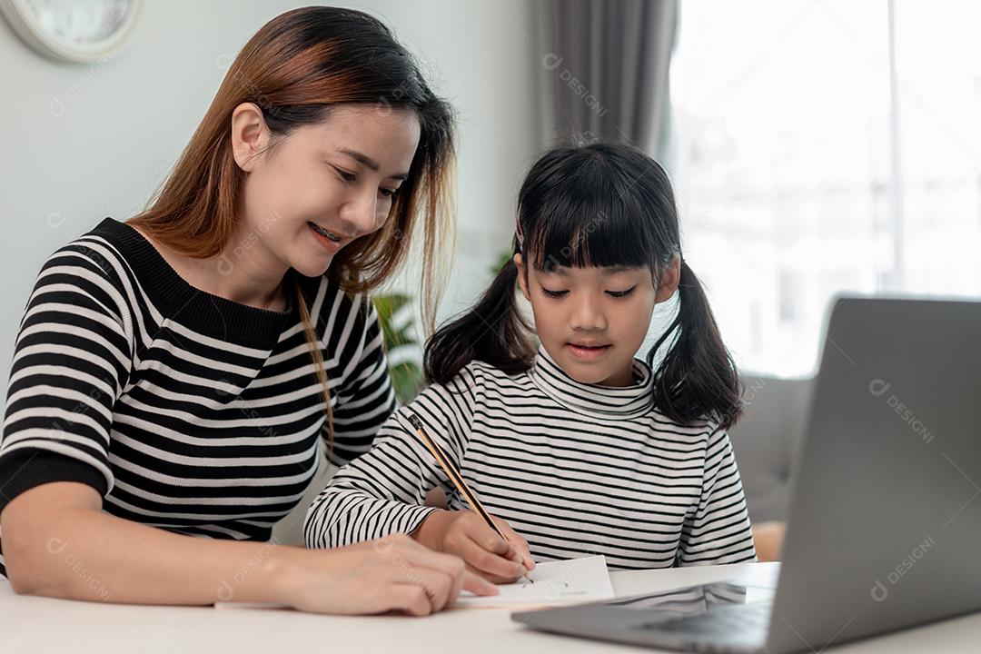 Garotinha asiática aprendendo aula online em casa com mãe