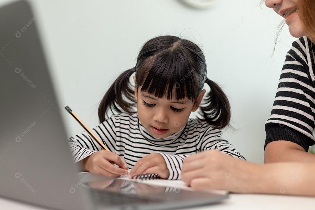 Garotinha asiática aprendendo aula online em casa com a mãe