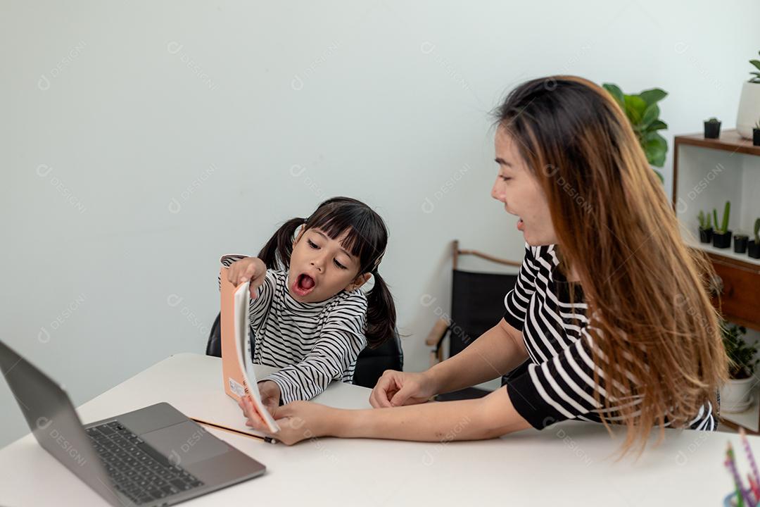 Garotinha asiática aprendendo aula online em casa com a mãe