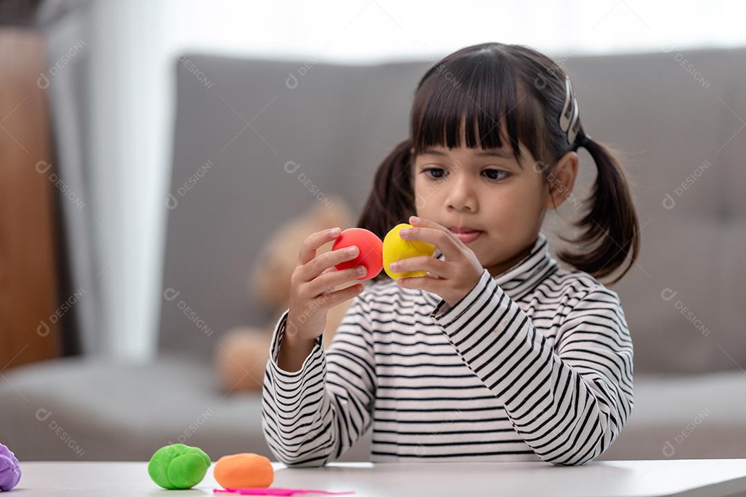 Crianças asiáticas brincam com formas de moldagem de argila, aprendendo brincando