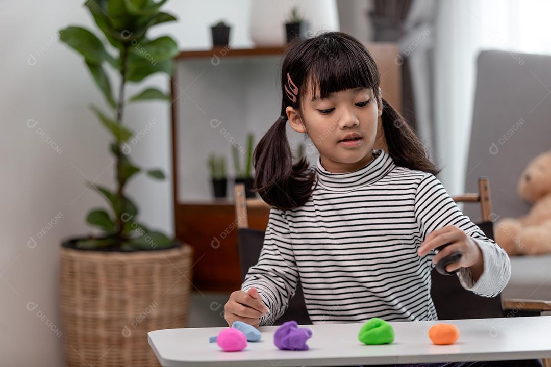 Crianças asiáticas brincam com formas de moldagem de argila, aprendendo brincando