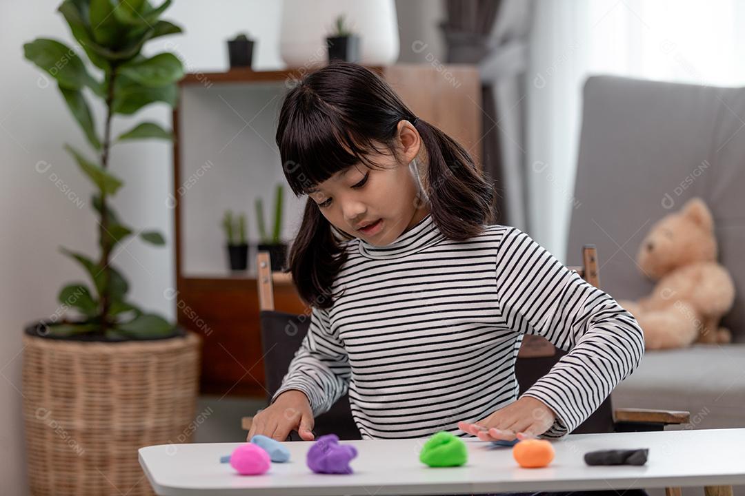 Crianças asiáticas brincam com formas de moldagem de argila, aprendendo brincando