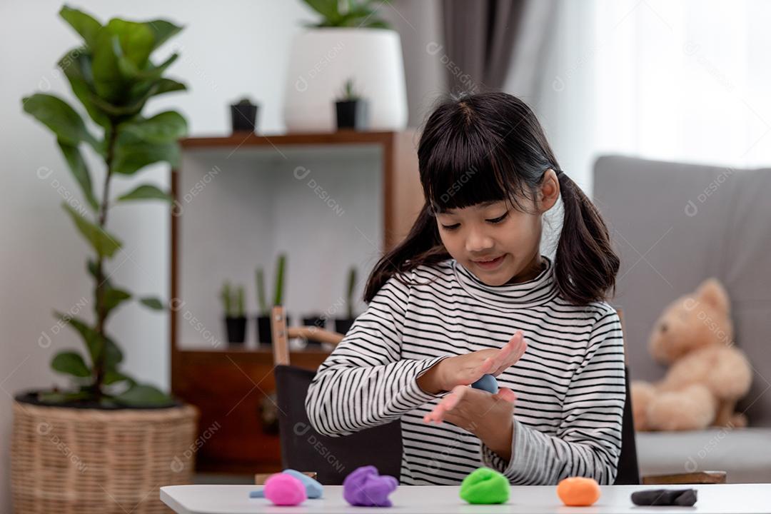 Crianças asiáticas brincam com formas de moldagem de argila, aprendendo brincando