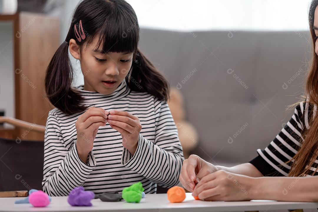 Crianças asiáticas brincam com formas de moldagem de argila, aprendendo brincando