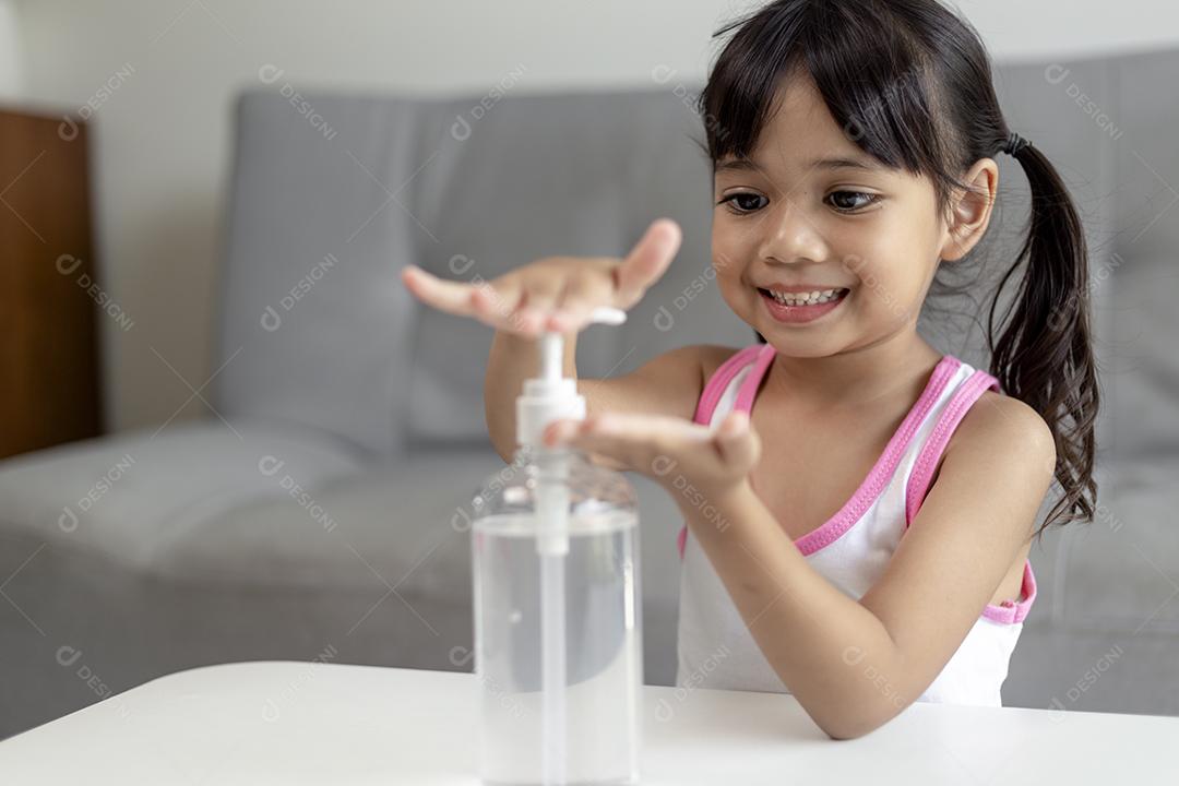 Menina asiática coloca bomba desinfetante de gel de álcool nas mãos