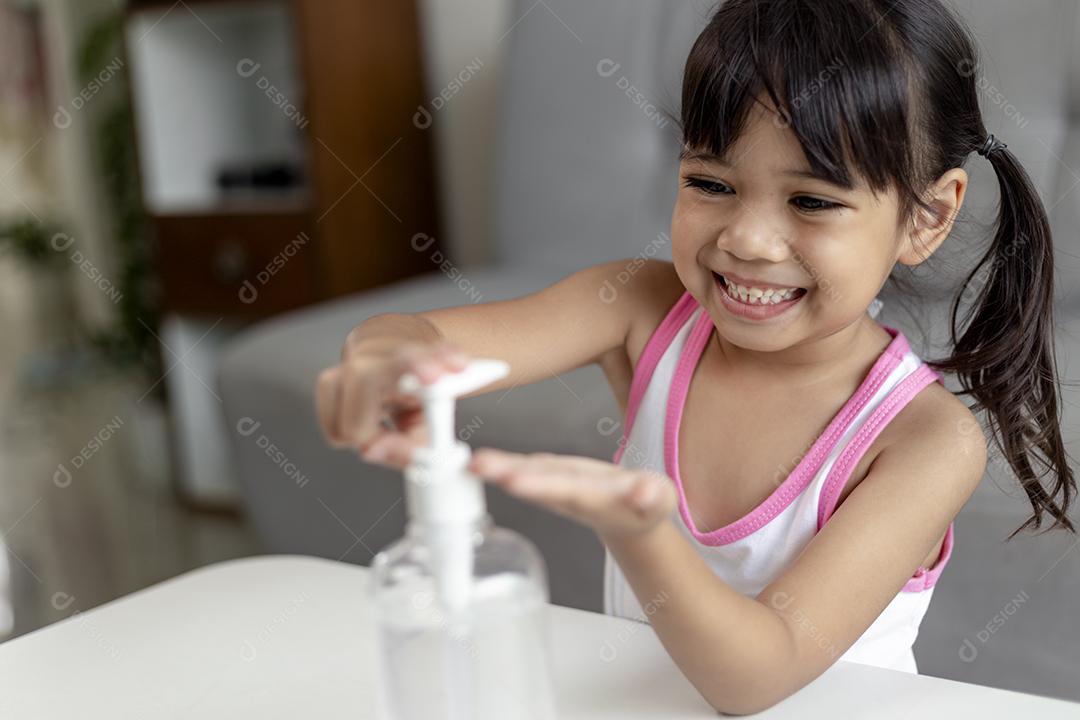 Menina asiática coloca bomba desinfetante de gel de álcool nas mãos