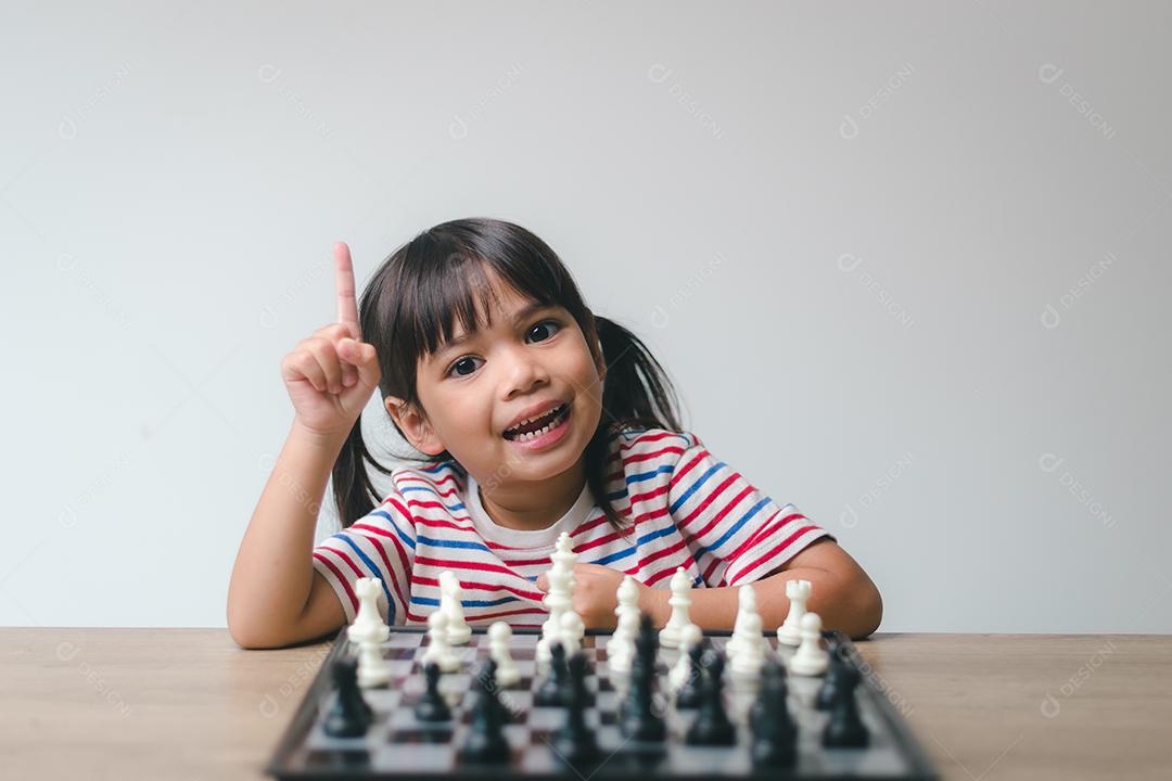 Menina asiática jogando xadrez em casa. um jogo de xadrez