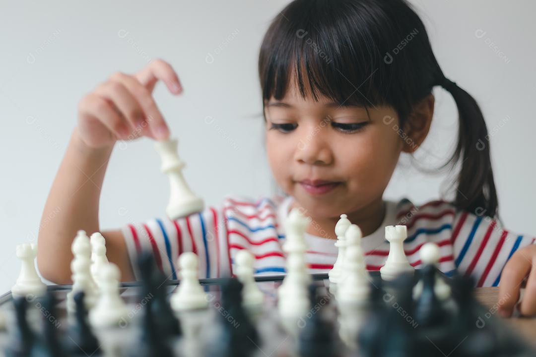 Menina asiática jogando xadrez em casa. um jogo de xadrez