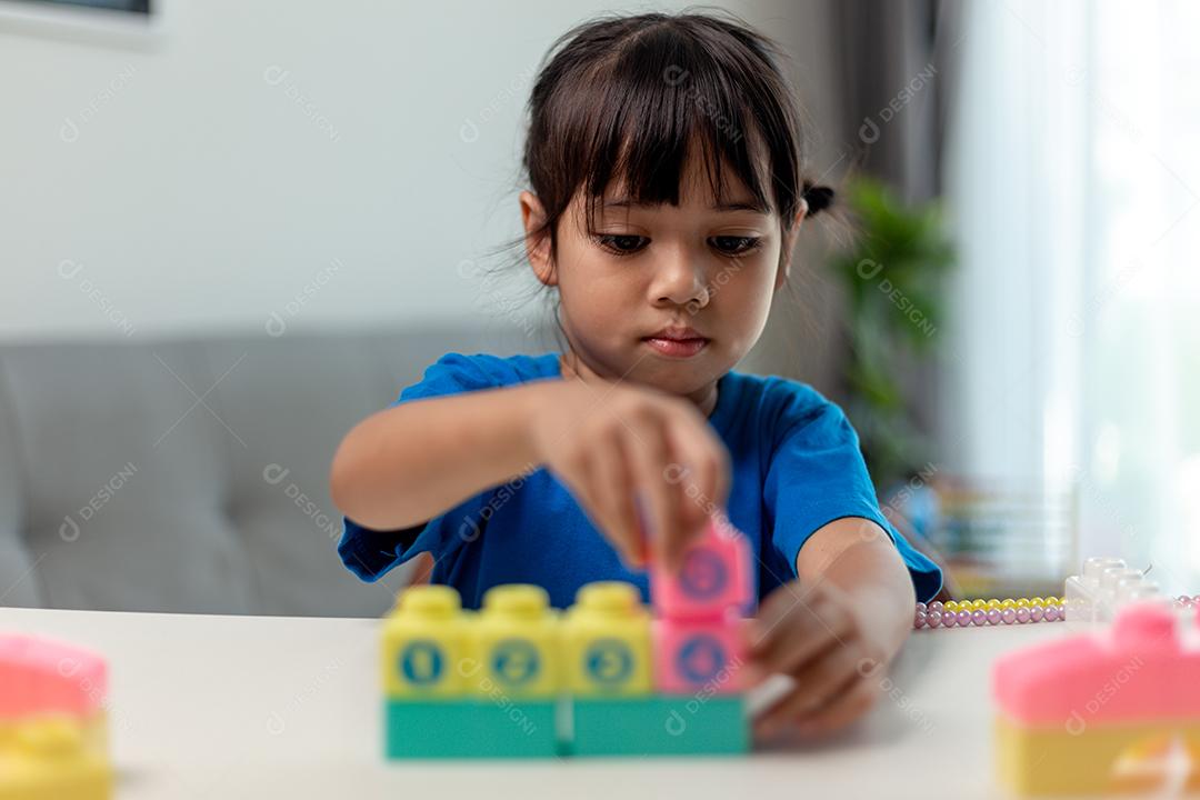 Menina asiática jogando blocos de brinquedo criativos para educação em casa