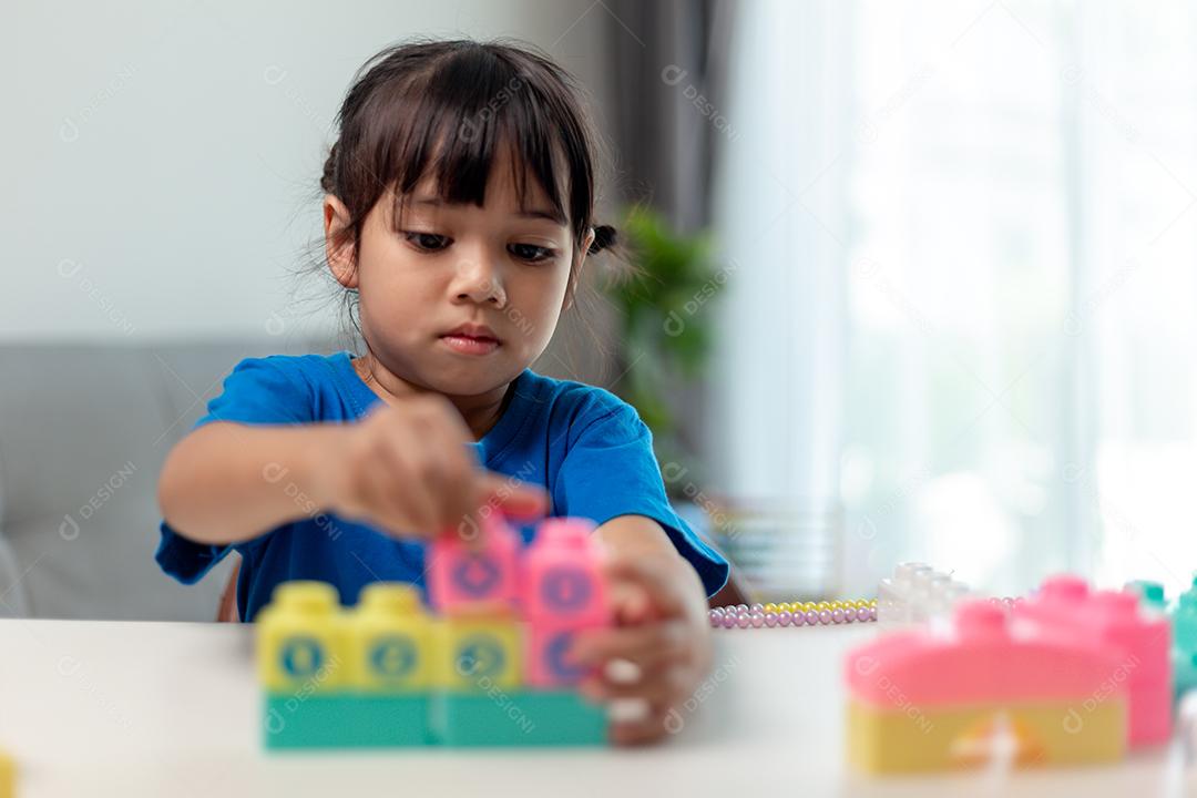 Menina asiática jogando blocos de brinquedo criativos para educação em casa