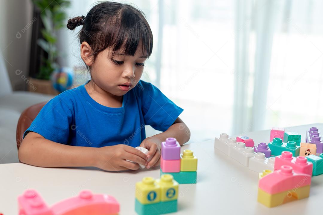 Menina asiática jogando blocos de brinquedo criativos para educação em casa