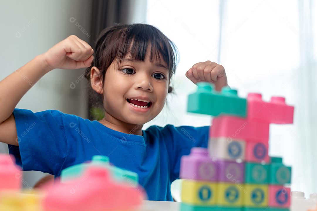 Menina asiática jogando blocos de brinquedo criativos para educação em casa
