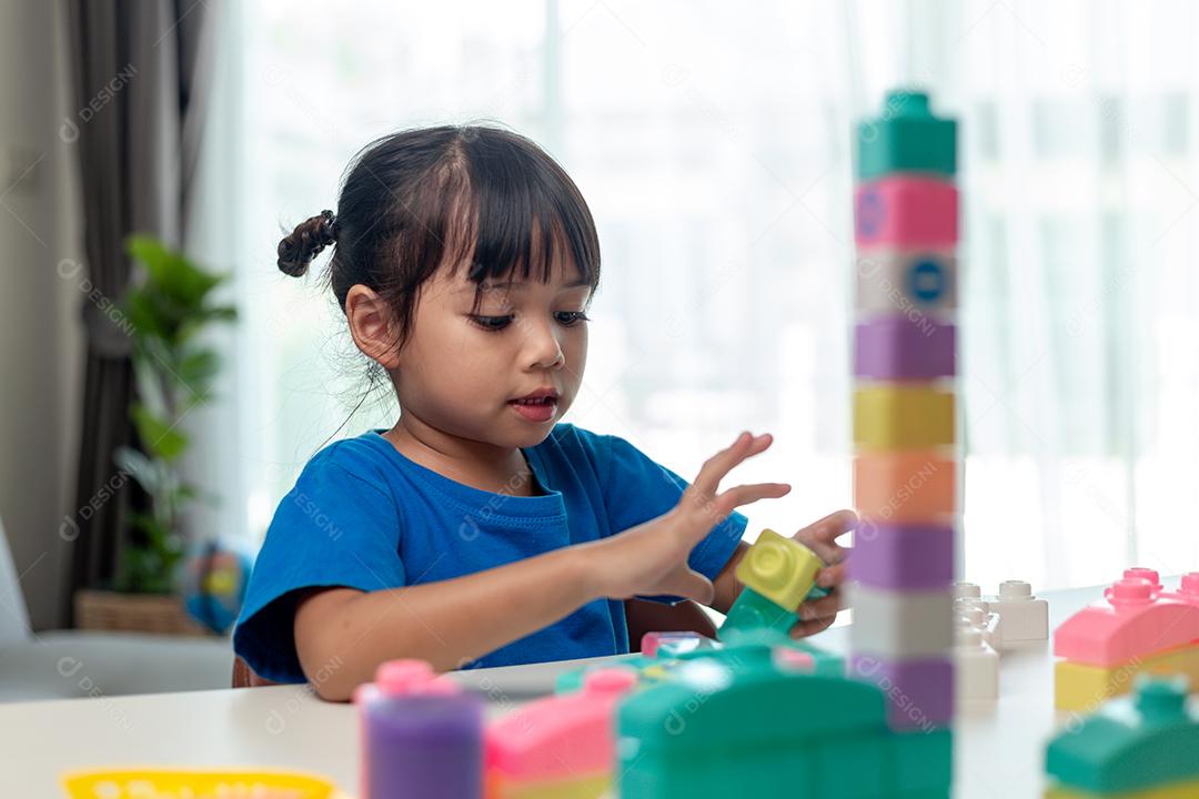 Menina asiática jogando blocos de brinquedo criativos para educação em casa