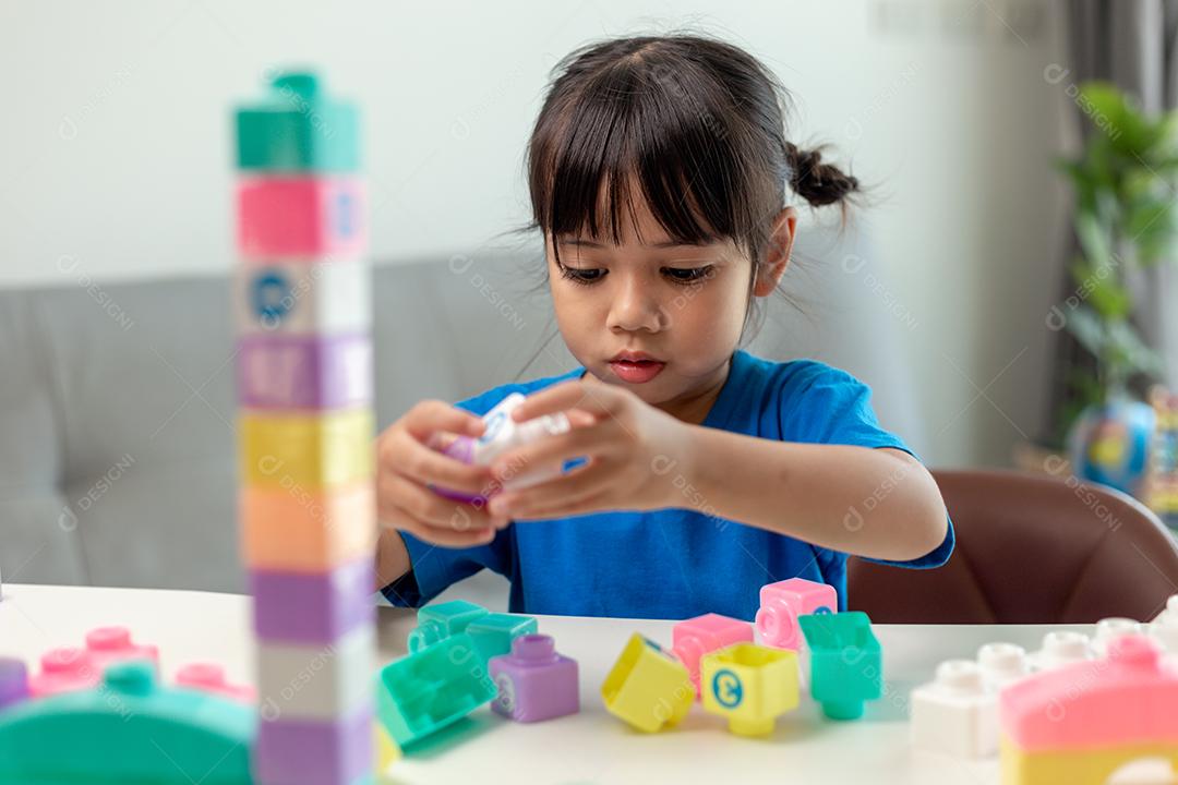 Menina asiática jogando blocos de brinquedo criativos para educação em casa