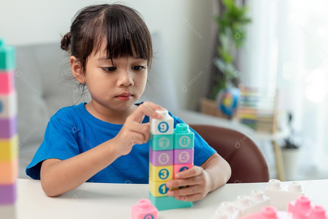 Menina asiática jogando blocos de brinquedo criativos para educação em casa